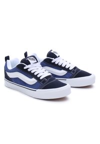 Adidași din suede bleumarin cu șireturi albe, dungi laterale albe și talpă din cauciuc. Prezentând texturi și detalii de cusătură contrastante.