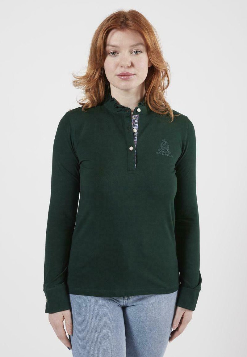 Polo à manches longues vert avec un plastron décoratif à boutons et un col festonné ; porte un logo brodé sur la poitrine.