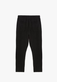 Schwarze, strukturierte Hose mit lockerer Passform, ausgestattet mit einem breiten elastischen Bund und zwei Gesäßtaschen. Keine sichtbaren Fronttaschen.