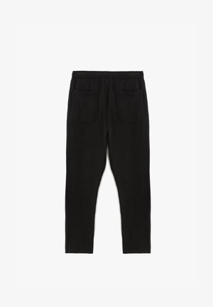 Schwarze, strukturierte Hose mit lockerer Passform, ausgestattet mit einem breiten elastischen Bund und zwei Gesäßtaschen. Keine sichtbaren Fronttaschen.