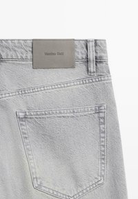 Gray denim jeans feature a back pocket and a gray leather patch with "Massimo Dutti" embossed. The texture is slightly distressed.
