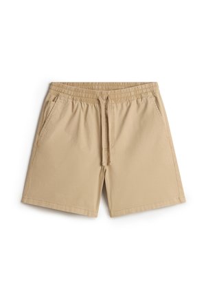 Pantaloni beige con un elastico in vita e lacci. Presentano due tasche laterali, una texture liscia e bordi rifiniti.