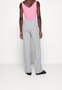 Szare spodnie w prążki o strukturalnym kroju, zestawione z dopasowanym różowym prążkowanym topem na ramiączkach, z designem V na plecach. Luźna sylwetka.