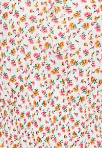 Tissu blanc avec petit imprimé floral orange et rose et texture froncée élastique smockée.