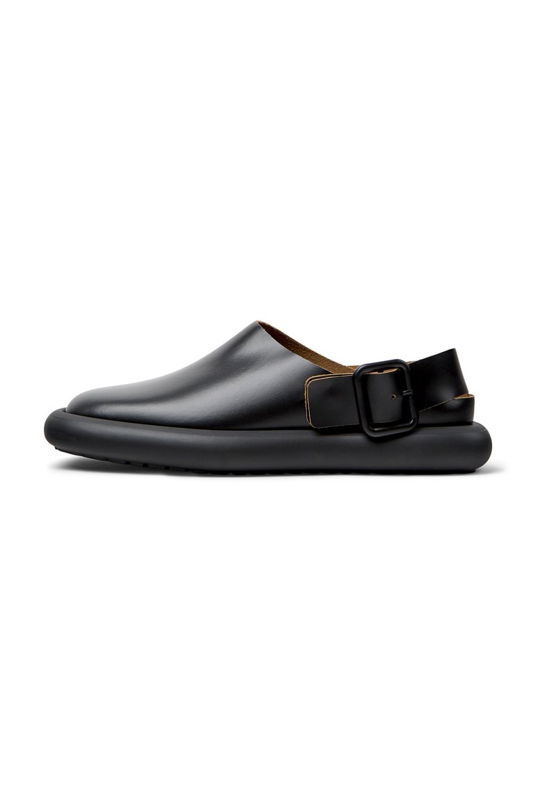Scarpe slip-on in pelle nera con punta arrotondata, fodera in pelle marrone a contrasto e una cintura con fibbia rettangolare sul tallone.