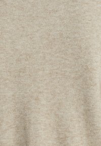 Tejido de punto beige con una textura suave. Color uniforme con ligeras variaciones y un patrón sutil y difuminado. Sin hardware o acentos notables.