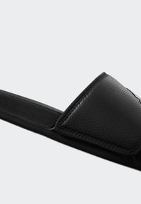 Black slide sandal featuring a textured synthetic upper with a padded strap and a flexible rubber sole, designed for comfort and ease of wear.