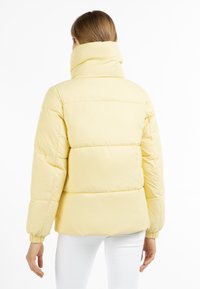 Geel gewatteerd jack met een hoge kraag, elastische boorden en horizontale stiksels. Gladde textuur en lichtgewicht ontwerp.