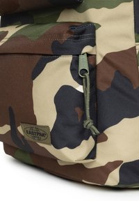 Zaino mimetico con motivi beige, marroni, verdi e neri. Tessuto strutturato, cuciture rinforzate e chiusura regolabile con coulisse.