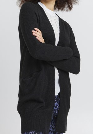 Sort cardigan lavet af blødt materiale med en løs pasform, åben front og to for-lommer, med lange ærmer og ribbet tekstur.