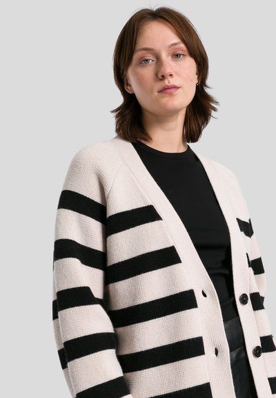 Cardigan a strisce in beige chiaro e nero. Caratterizzato da un colletto a V, maniche lunghe e bottoni lungo la parte anteriore. Realizzato in un morbido filato testurizzato.