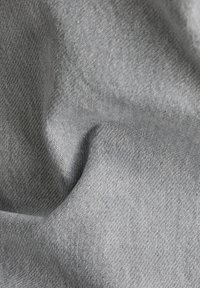 Tissu tissé gris avec une texture douce, présentant un motif en chevrons. Le matériau est léger et flexible, adapté à diverses applications.