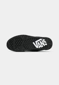 Čierna gumová podrážka s textúrovaným gripovým vzorom, s výrazným bielym logom "VANS". Zaoblený dizajn špičky a päty.
