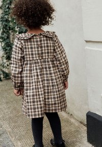 Brown plaid dress with a scalloped collar and button-down back. Long sleeves, gathered waist, paired with dark tights and black shoes.