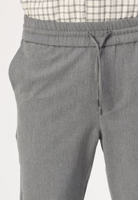 Grijze joggers van gestructureerde stof met een elastische tailleband en koord. Beschikt over zijzakken en een tapered fit.