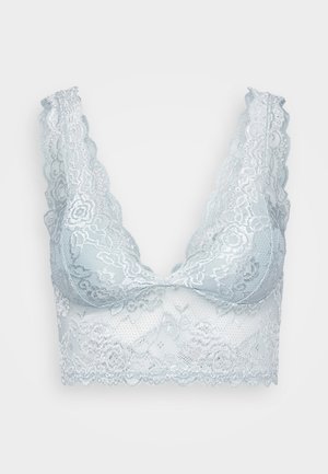 Světle modrý krajkový bralet s vlnkovanými okraji, hlubokým výstřihem do V a květinovými vzory. Látka má jemnou, průhlednou strukturu.