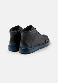 Sneaker alte nere in pelle con finitura testurizzata, punta rotonda e collare imbottito, dotate di suola in gomma scura e un branding discreto.