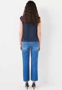 Navy short-sleeve top paired with high-waisted, wide-leg blue jeans. Smooth fabric, light fading, and a classic five-pocket design.