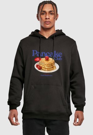 Hoodie noir avec un graphique à l'avant représentant des pancakes avec du sirop et des framboises, étiqueté "Pancake Club" en texte bleu. Poche avant incluse.