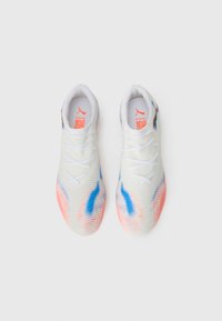 Weiße Sportschuhe mit einem strukturierten Obermaterial, das blaue und pinke Akzente aufweist, traditionellen Schnürsenkeln und einem Logo auf der Zunge.