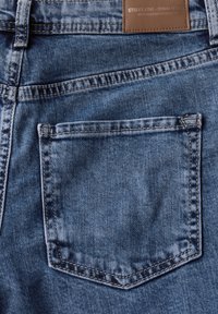 Blaue Jeans aus Denim mit einer einzelnen Gesäßtasche mit gestickten Kanten und einem braunen Lederetikett am Bund.