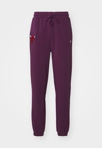 Pantaloni della tuta viola realizzati in tessuto morbido, con una vita elastica dotata di cordino e un logo di toro rosso sulla gamba sinistra. Caviglie con polsini elastici.