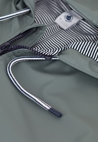 Green waterproof jacket with a striped inner lining, featuring a zipper closure, drawstring hood, and smooth, shiny exterior texture.
