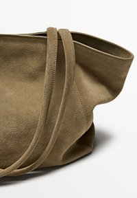 Suède totebag in gedempt bruin, met twee lange handvatten, een zachte textuur en een ontspannen vorm met een open bovenkant.