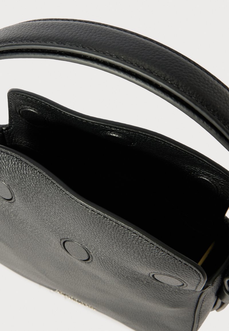 Sac à main en cuir noir avec une surface texturée, une poignée supérieure et une fermeture à pression. Intérieur ouvert sans compartiments visibles.
