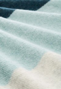 Tissu doux et texturé affichant un dégradé de bleu clair, aqua et blanc cassé avec des variations subtiles de teinte et une sensation lisse.