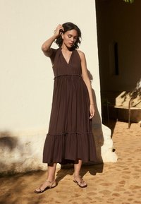 Pruun halter maxi kleit kihise äärega, pehme kangaga ja lõdva siluetiga. Kombleeritud lame tossudega.