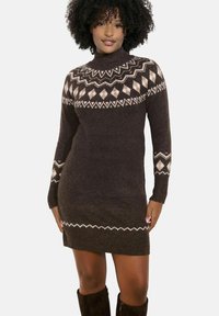 Abito maglione marrone con collo alto, caratterizzato da un motivo geometrico color crema sul petto e sulle maniche, con una silhouette aderente.