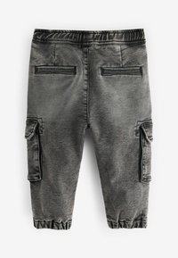 Pantalones cargo grises con textura cepillada, cinturilla elástica, puños acanalados y dos bolsillos cargo en los laterales. Presenta detalles de costura sutiles.