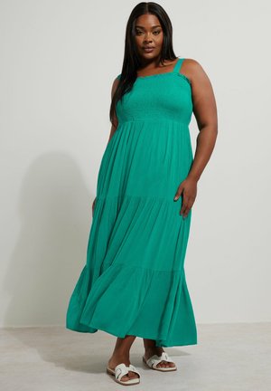 Groene maxidress met een gerimpelde bodice, dikke banden en een gelaagde rok. Gemaakt van lichtgewicht stof met een vloeiende uitstraling en golvende afwerking.