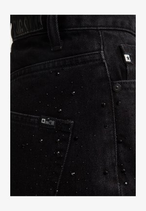 Czarne dżinsy o teksturowanej powierzchni z rozproszonymi czarnymi koralikami i metką marki na tylnej kieszeni.