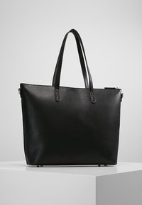 Černá kožená taška přes rameno s dvojitými uchy, obdélníkový tvar, hladký povrch a minimalistický design. Obsahuje zipové uzavření a elegantní povrchovou úpravu.