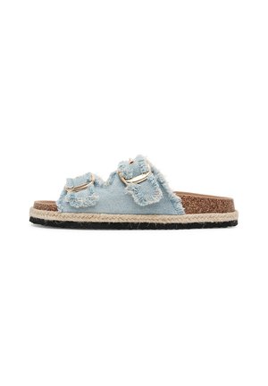 Jeans-Sandalen in Hellblau mit ausgefransten Kanten, ausgestattet mit zwei goldenen Schnallen und einer strukturierten Korksohle mit geflochtenem Textilakzent.