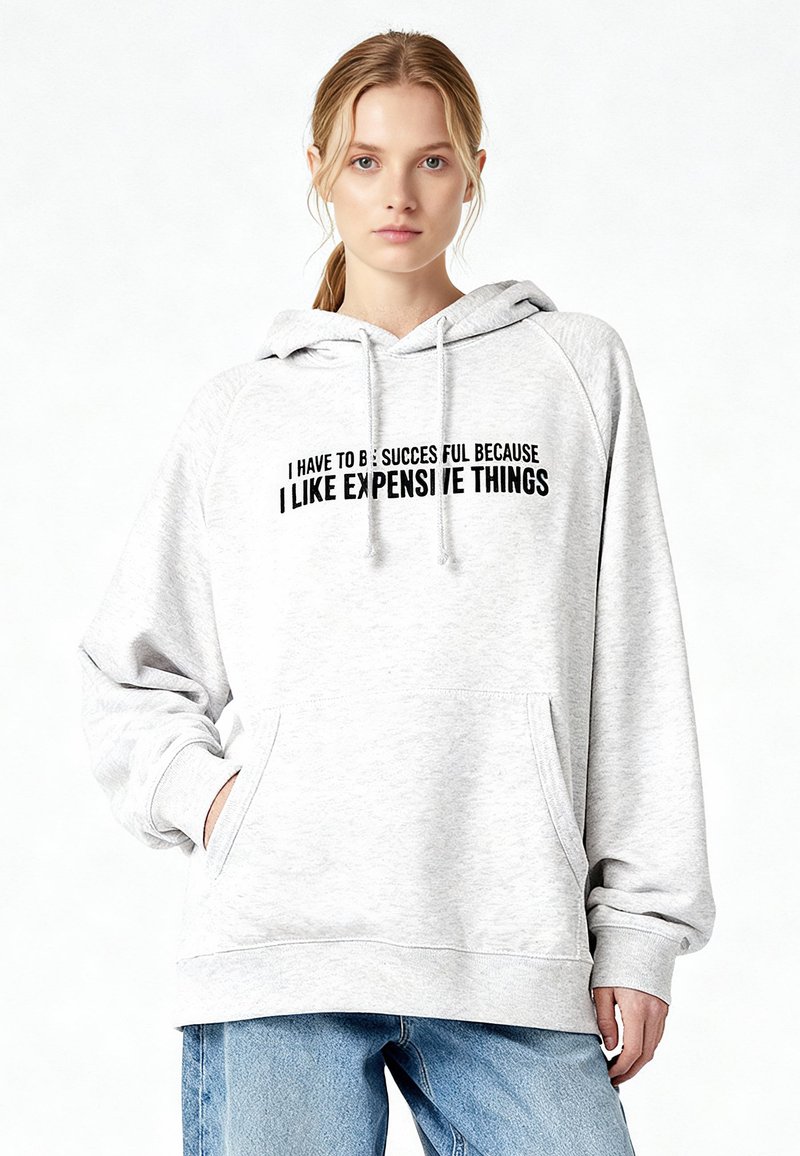 Felpa grigia con cappuccio a coulisse, tasca frontale e scritta nera che recita: "DEVO AVERE SUCCESSO PERCHÉ MI PIACCIONO LE COSE COSTOSE."