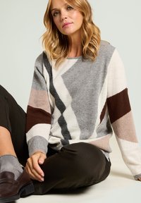 Wielokolorowy sweter z geometrycznymi wzorami w odcieniach szarości, beżu i brązu. Miękka dzianina o luźnym kroju i długich rękawach.