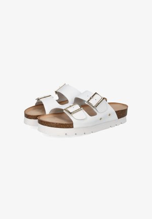 White slide sandals with two adjustable straps, gold-tone buckles, a cork midsole, and a textured white rubber sole.