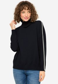 Donker marineblauwe pullover trui met een hoge ribgebreide kraag, brede mouwen en contrasterende witte zijkanten. Zachte, gestructureerde breimateriaal.
