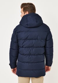 Marineblaue Steppjacke mit Kapuze, ausgestattet mit einem gesteppten Muster und elastischen Bündchen. Weiche, glatte Textur mit lockerem Schnitt und strapazierfähigen Nähten.