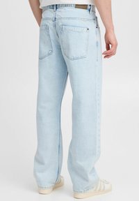 Lichtblauwe denim jeans met een recht model, twee achterzakken en een taillebandpatch. De stof is glad met minimale stikdetails.