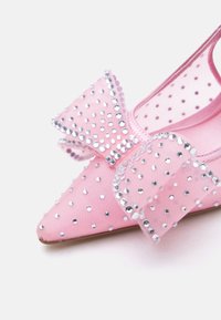 Rozā plakana kurpe ar smailiem galiem, rotāta ar lielu loku un pārklāta ar maziem sudrabotiem rhinestones.