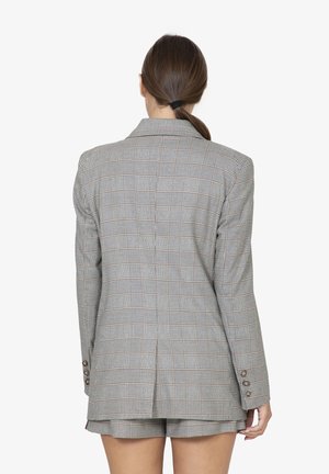 Blazer a quadri grigio con una vestibilità su misura, apertura singola e dettagli con quattro bottoni sui polsini. Il materiale è una stoffa testurizzata con linee a contrasto.