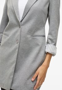 Blazer grigio realizzato in tessuto testurizzato, con chiusura a singolo bottone, tasche laterali e dettaglio con maniche rigate arrotolate.
