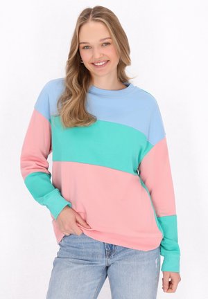 Bluza w kolorze blokowym z jasnoniebieskimi, zielonymi i różowymi sekcjami. Ma klasyczny okrągły dekolt oraz długie rękawy z prążkowanymi mankietami. Miękka faktura.
