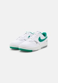Un paio di scarpe Nike bianche con logo swoosh verde, fodera verde e dettagli verdi e grigi sulle suole, mostrato su uno sfondo bianco.