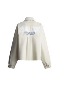 Beige lange mouwen jas met elastische manchetten, kraag en de opdruk "RED BULL RACING Competing SINCE 2004" op de achterkant.