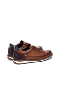 Zapatos de cuero marrón con textura suave, que presentan un diseño de cordones, acentos marrón oscuro en el tacón y una suela de color crema.